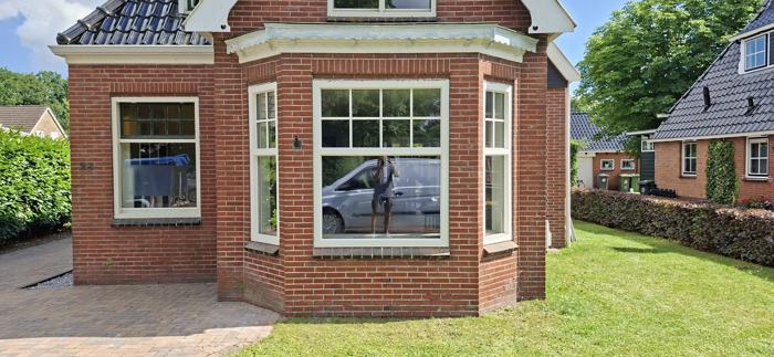 Witte kunststof erker met draai-kiepramen in rode gevel